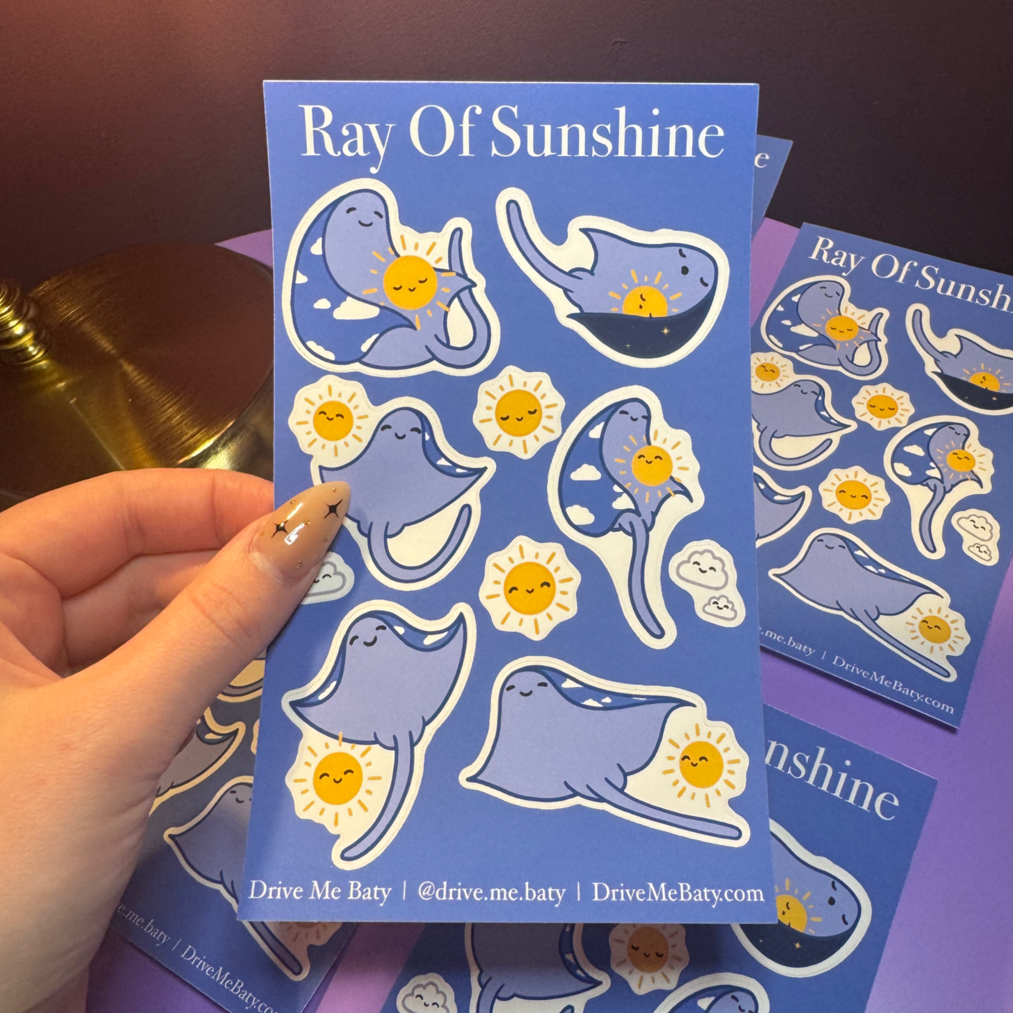 Sticker sheet with cartoon characters and 'Ray of Sunshine' text held by a hand.
