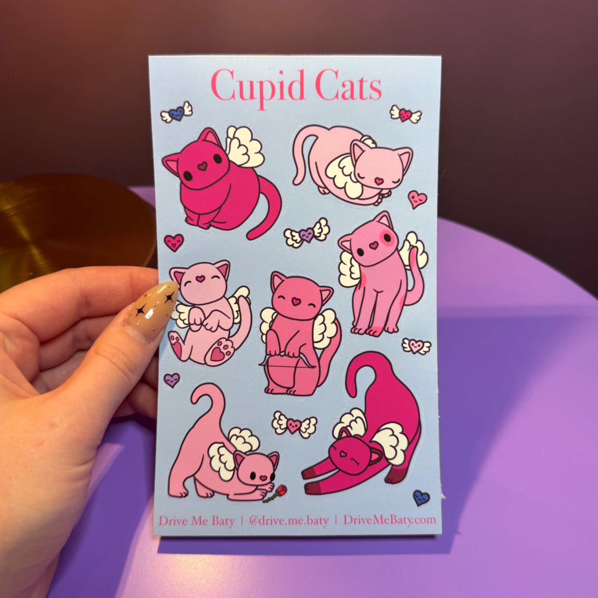 Sticker sheet with pink cupid cats on a purple background